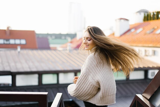 Une belle jeune brune sourit largement, ses cheveux se développant dans le vent alors qu'elle tourne.