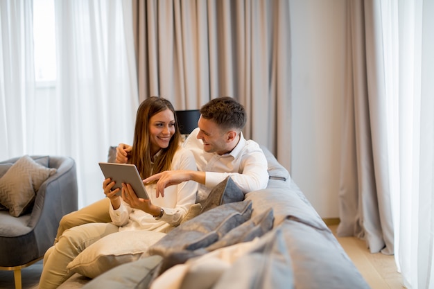 Belle jeune couple avec tablette numérique dans la chambre