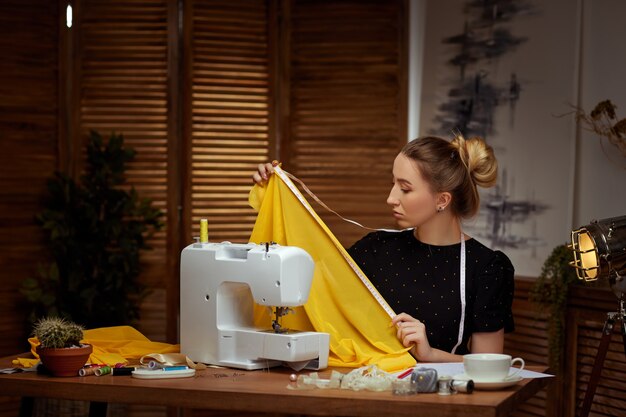 Belle jeune couturière travaillant sur une machine à coudre