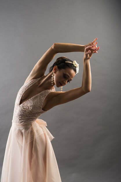 Belle jeune danseuse de ballet en maillot de bain beige posant sur des pointes sur studio gris clair