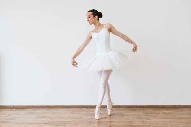 Une belle jeune danseuse pose sur le fond du studio.