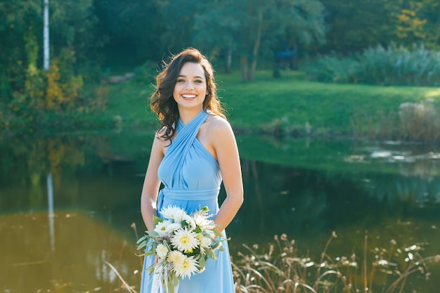 Belle jeune demoiselle d'honneur aux cheveux bouclés posant lors de la cérémonie de mariage