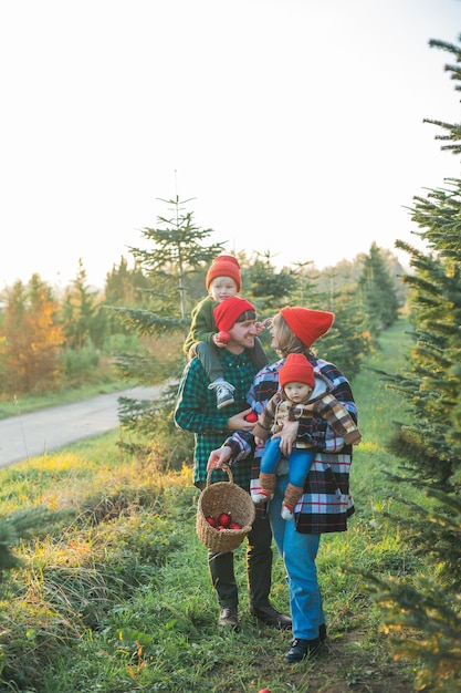 Une belle jeune famille choisit un sapin de Noël sur le marché Vacances d'hiver festives pour les parents et les jeunes enfants respectueux de l'environnement