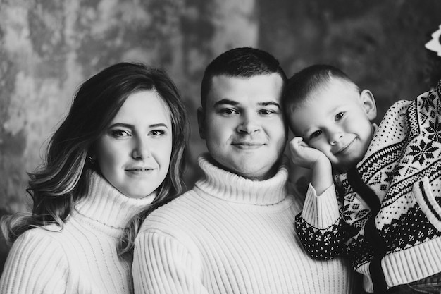 belle jeune famille dans des pulls confortables avec col roulé. Portrait de mère, père et fils souriant