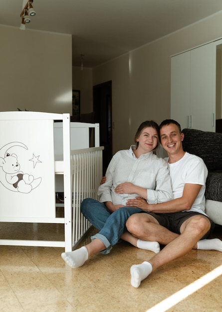 Photo une belle jeune famille est assise près d'un berceau en attendant leur bébé à naître.