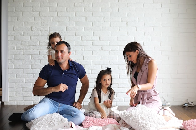 Belle jeune famille avec filles lors d'une séance photo dans un studio blanc