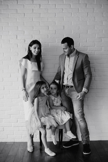 Belle jeune famille avec filles lors d'une séance photo dans un studio blanc