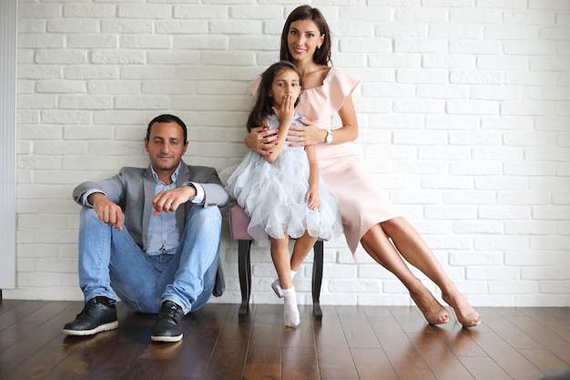 Belle jeune famille avec filles lors d'une séance photo dans un studio blanc