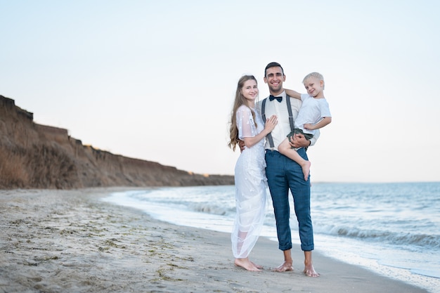 Belle jeune famille sur fond de mer. Papa garde le petit-fils entre ses mains. Famille heureuse