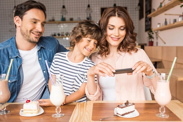 belle jeune famille prenant une photo de dessert avec un smartphone au café