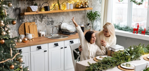 Belle jeune famille profitant de leurs vacances ensemble, décorant le sapin de Noël, arrangeant les lumières de Noël et s'amusant.