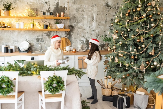 Belle jeune famille profitant de leurs vacances ensemble, décorant le sapin de Noël, arrangeant les lumières de Noël et s'amusant.