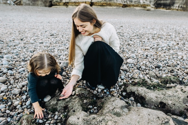 Une belle jeune famille sur le rivage sablonneux de l'océan se détendre et s'amuser