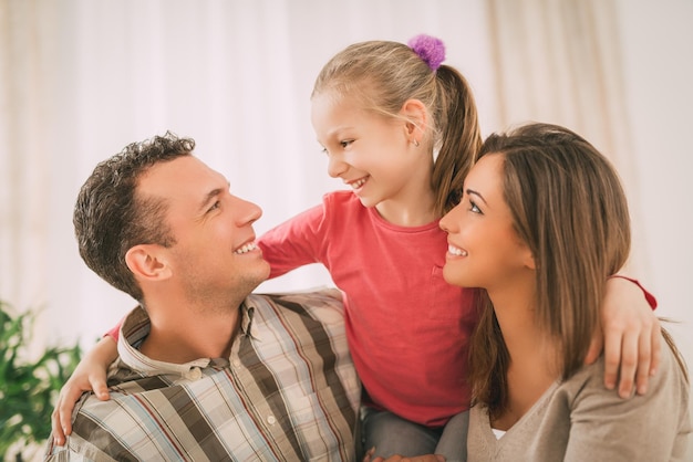 Belle jeune famille souriante se reposant sur un canapé dans le salon.