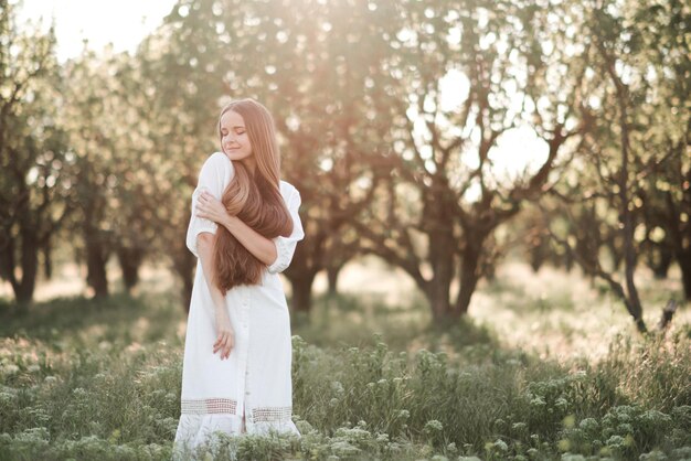 Belle jeune femme adulte aux longs cheveux blonds debout dans le jardin