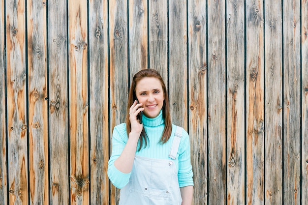 Belle jeune femme adulte parlant sur smartphone avec un fond en bois