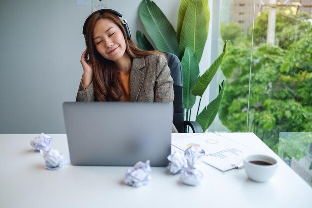 Une belle jeune femme d'affaires aime écouter de la musique pour soulager le stress au travail