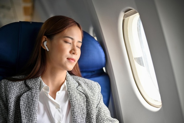 Belle jeune femme d'affaires asiatique détendue en faisant une sieste s'endormir pendant un vol