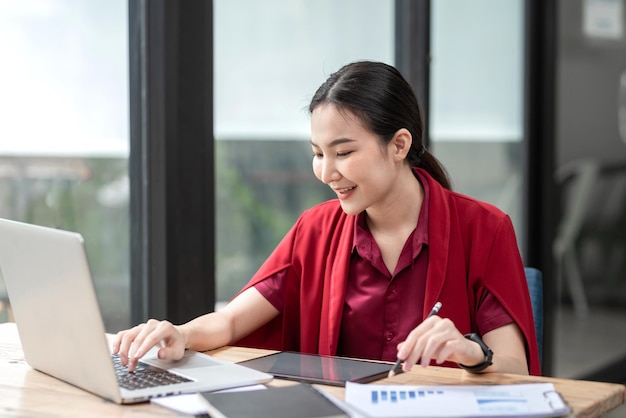 Belle jeune femme d'affaires asiatique utilisant un clavier d'ordinateur portable avec un diagramme d'informations au bureau.