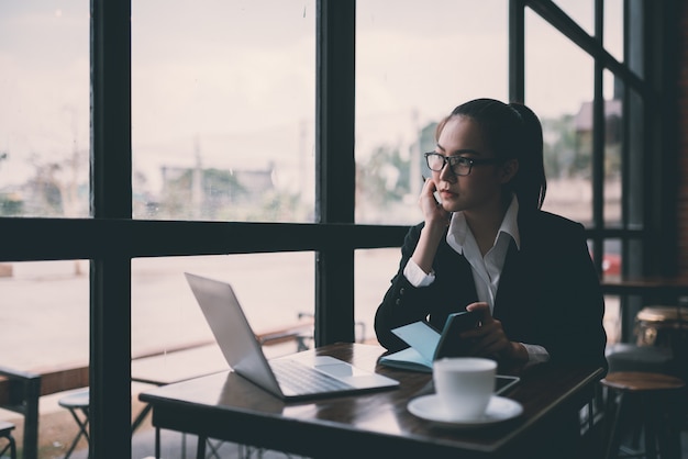 Photo belle jeune femme d'affaires assis à table et prendre des notes. dans le café