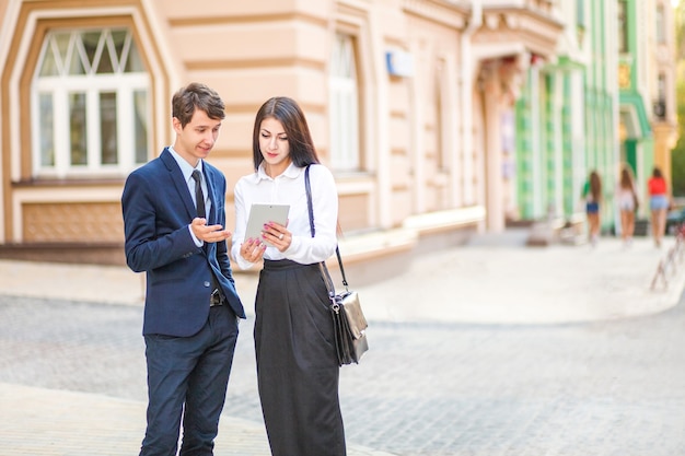 Belle jeune femme d'affaires et bel homme d'affaires en costume formel utilisent une tablette numérique