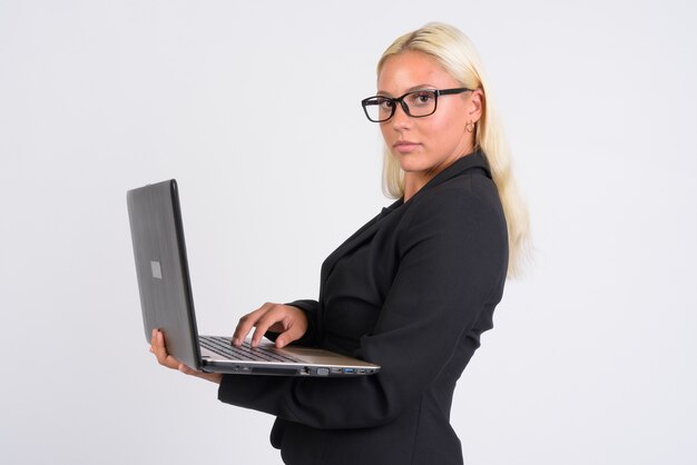 Belle jeune femme d'affaires blonde contre le mur blanc