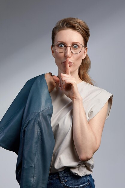 Belle jeune femme d'affaires caucasienne en studio sur fond gris Charmante et confiante femme blonde sérieuse en veste bleu foncé décontractée portant des lunettes