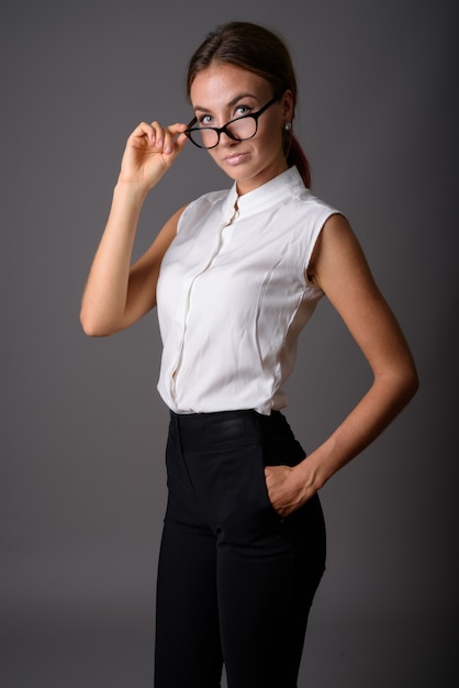 Belle jeune femme d'affaires contre le mur gris