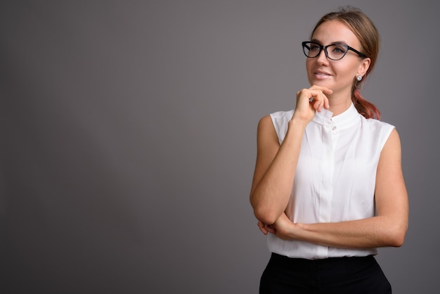 Belle jeune femme d'affaires contre le mur gris