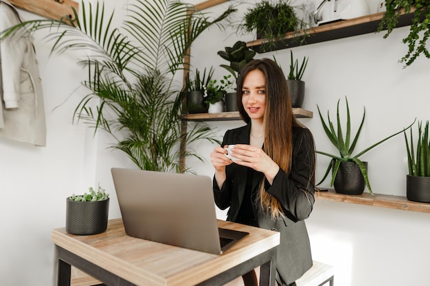 Belle jeune femme d'affaires dans une veste est assise à une table dans un confortable café hipster