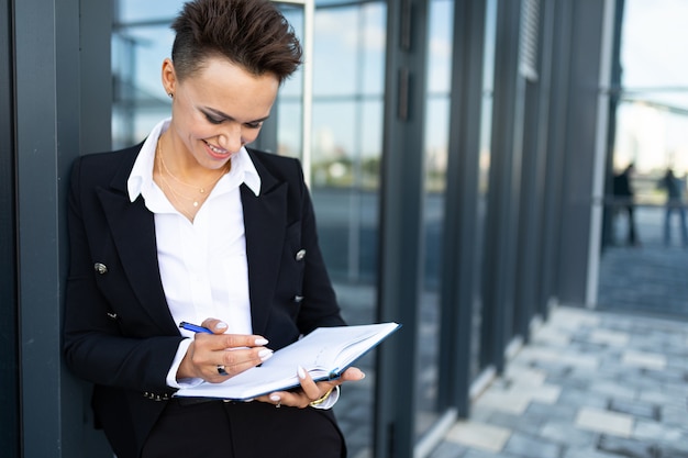 Belle jeune femme d'affaires posant contre un bâtiment moderne