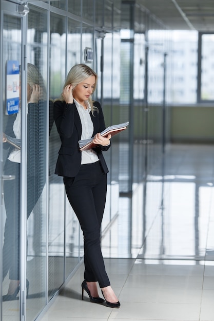 Belle jeune femme d'affaires à la recherche de documents au bureau.