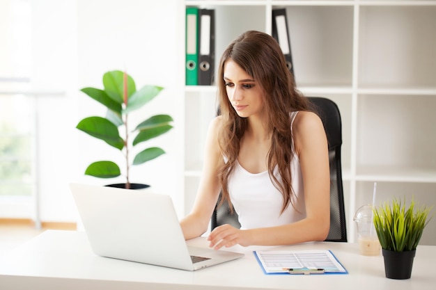 Belle jeune femme d'affaires travaillant sur ordinateur portable dans un bureau moderne et lumineux