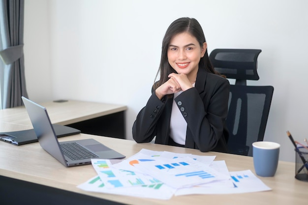 Belle jeune femme d'affaires travaillant sur ordinateur portable avec des documents dans un bureau moderne