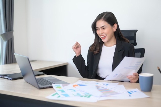 Belle jeune femme d'affaires travaillant sur ordinateur portable avec des documents dans un bureau moderne