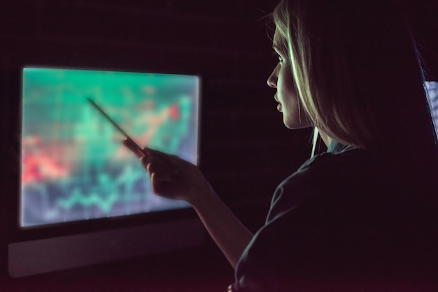 Belle jeune femme d'affaires travaille avec un ordinateur au bureau la nuit