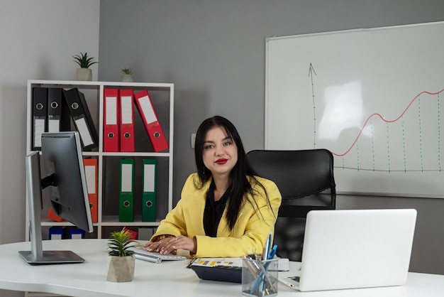 belle jeune femme d'affaires utilisant un ordinateur portable et travaillant avec des documents financiers au bureau