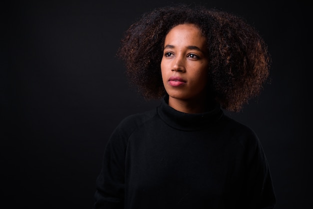 belle jeune femme africaine aux cheveux afro sur fond noir