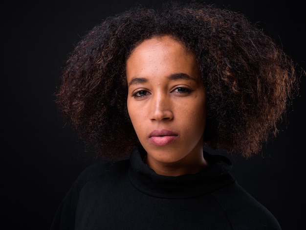 belle jeune femme africaine aux cheveux afro sur fond noir