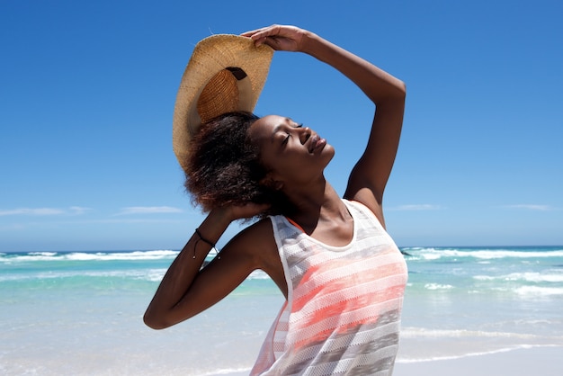 Belle jeune femme africaine avec un chapeau qui pose à l&#39;extérieur