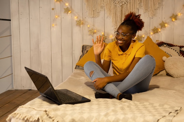 Belle jeune femme africaine à faire ses devoirs à la maison sur le lit