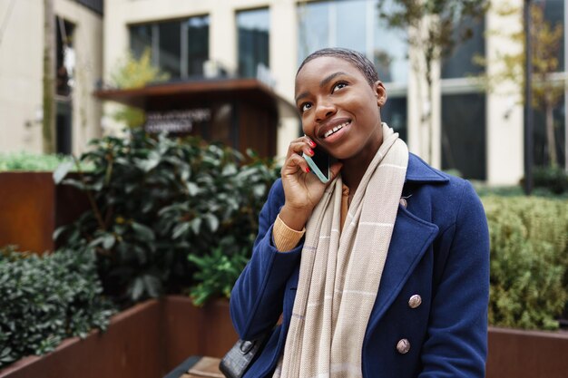 Une belle jeune femme africaine qui utilise un téléphone portable dans la rue.