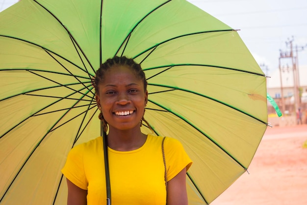 Belle jeune femme africaine utilisant un parapluie pour se protéger sous un temps très ensoleillé