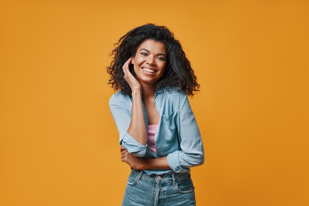 Belle jeune femme africaine en vêtements décontractés regardant la caméra et souriant