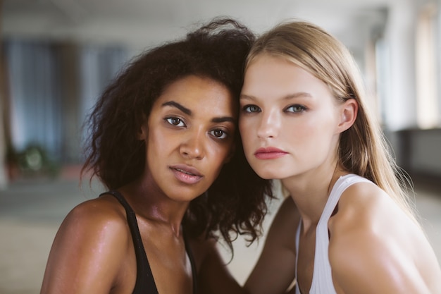 Belle jeune femme afro-américaine aux cheveux bouclés foncés et femme aux cheveux blonds pensivement tout en passant du temps ensemble