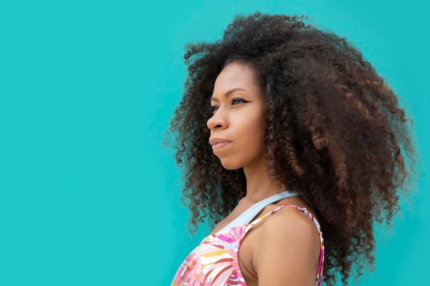 Belle jeune femme afro de profil sur fond bleu aigue-marine