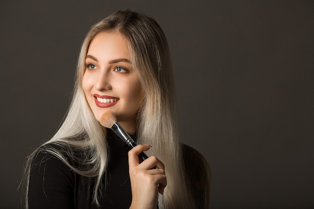 Belle jeune femme à l'aide de maquillage