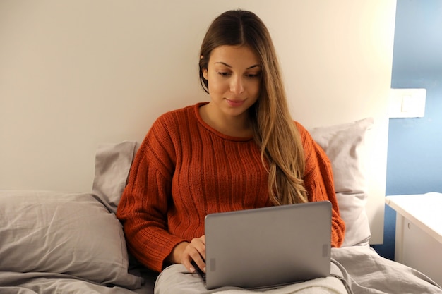 Belle Jeune Femme à L'aide D'un Ordinateur Portable Au Lit