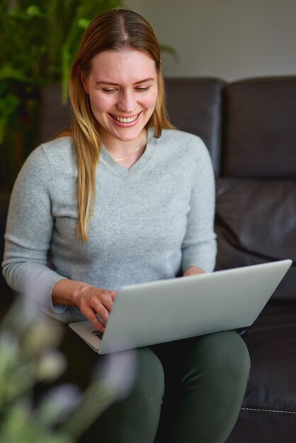 Belle jeune femme à l'aide d'un ordinateur portable à la maison