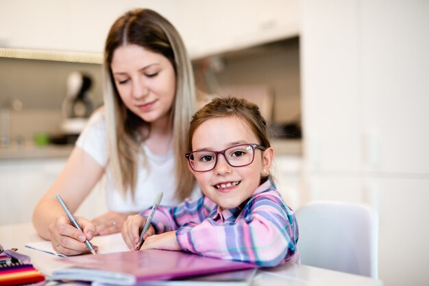 Belle jeune femme aide sa jeune sœur à faire ses devoirs.